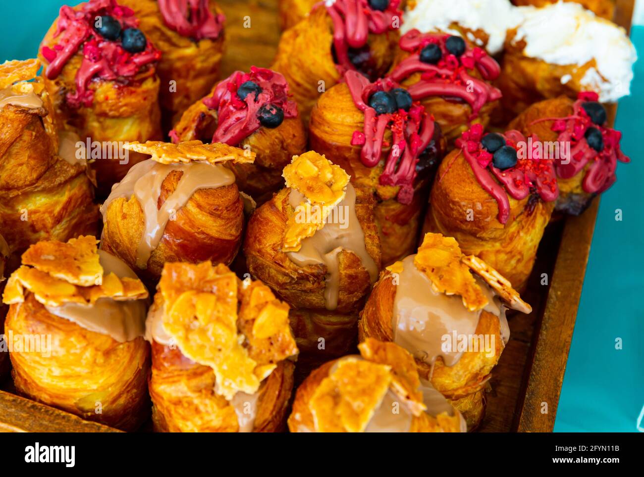 Holztablett mit verschiedenen süßen Cruffins und verschiedenen Cremes Stockfoto