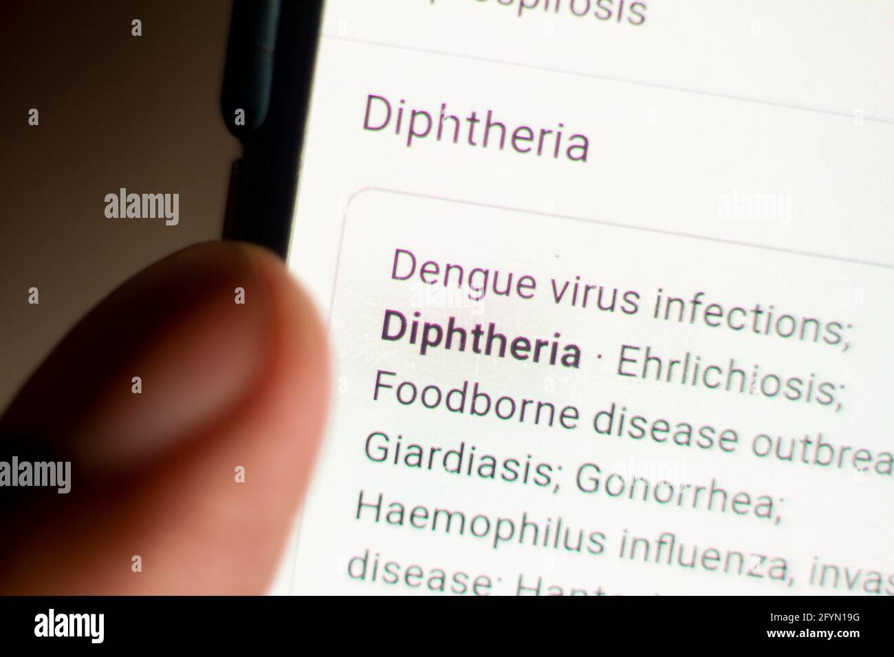 Diphtheria News auf dem Handy.Handy in den Händen. Selektiver Fokus und chromatische Aberration Effekte. Stockfoto