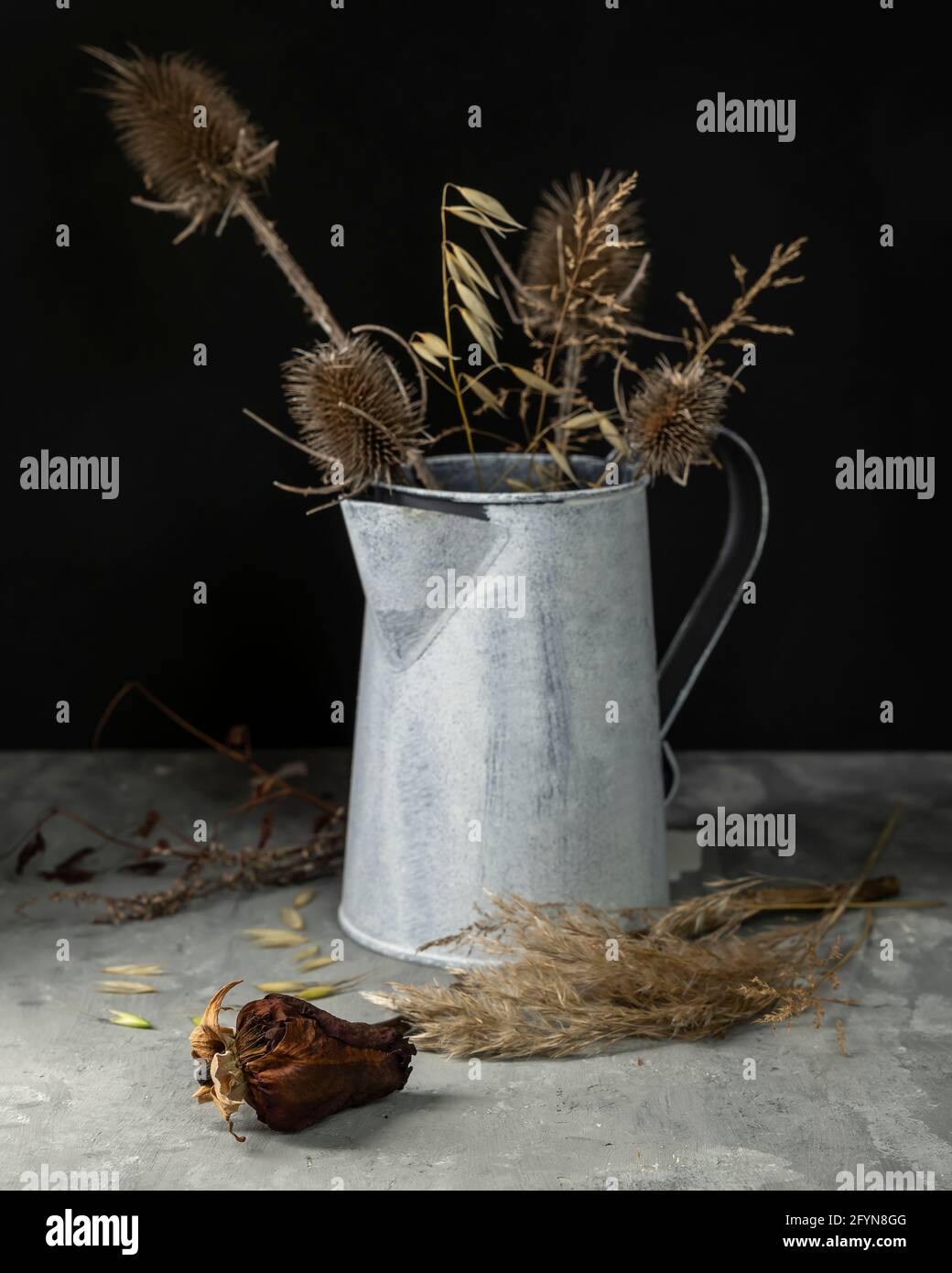 Zusammensetzung aus Blumen und getrockneten Pflanzen, von denen ein Teil in einer Zinnvase Stockfoto
