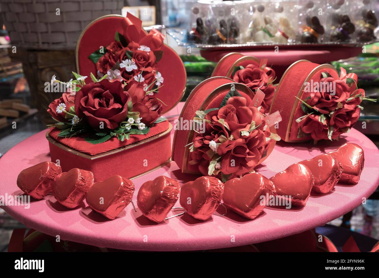 Romantische Dekoration mit Blumen und Schokoladenherzen in sanftem Rot Stockfoto