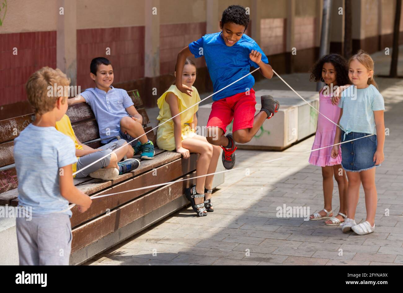 Mexikanischer Junge spielen Gummiband springen Spiel mit europäischen  Freunden und lachen im Freien Stockfotografie - Alamy