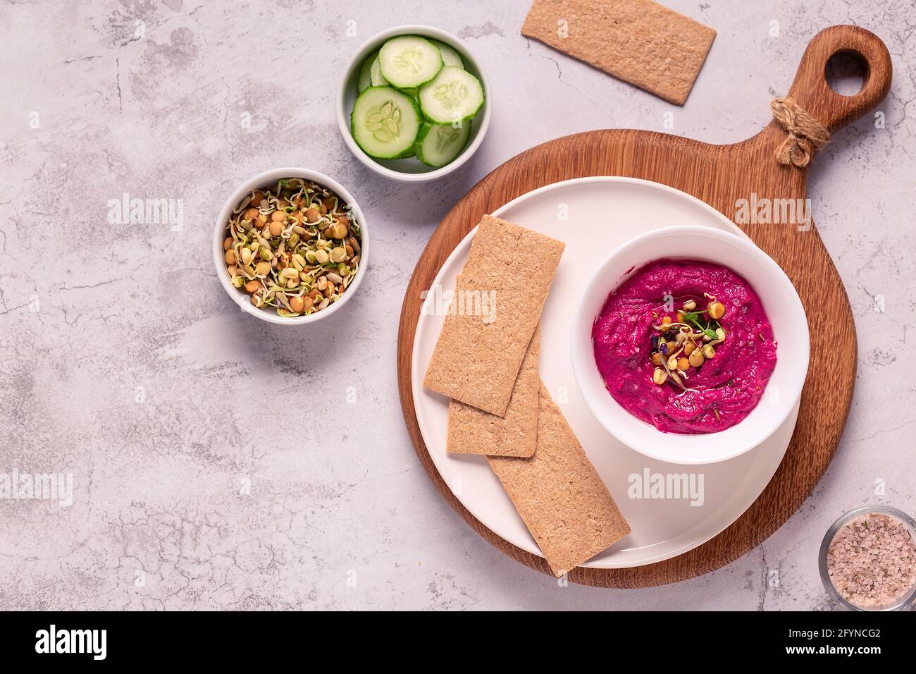 Gerösteter Rübenhummus mit gekeimtem Getreide, Gurke und Knäckebrot, Draufsicht. Stockfoto