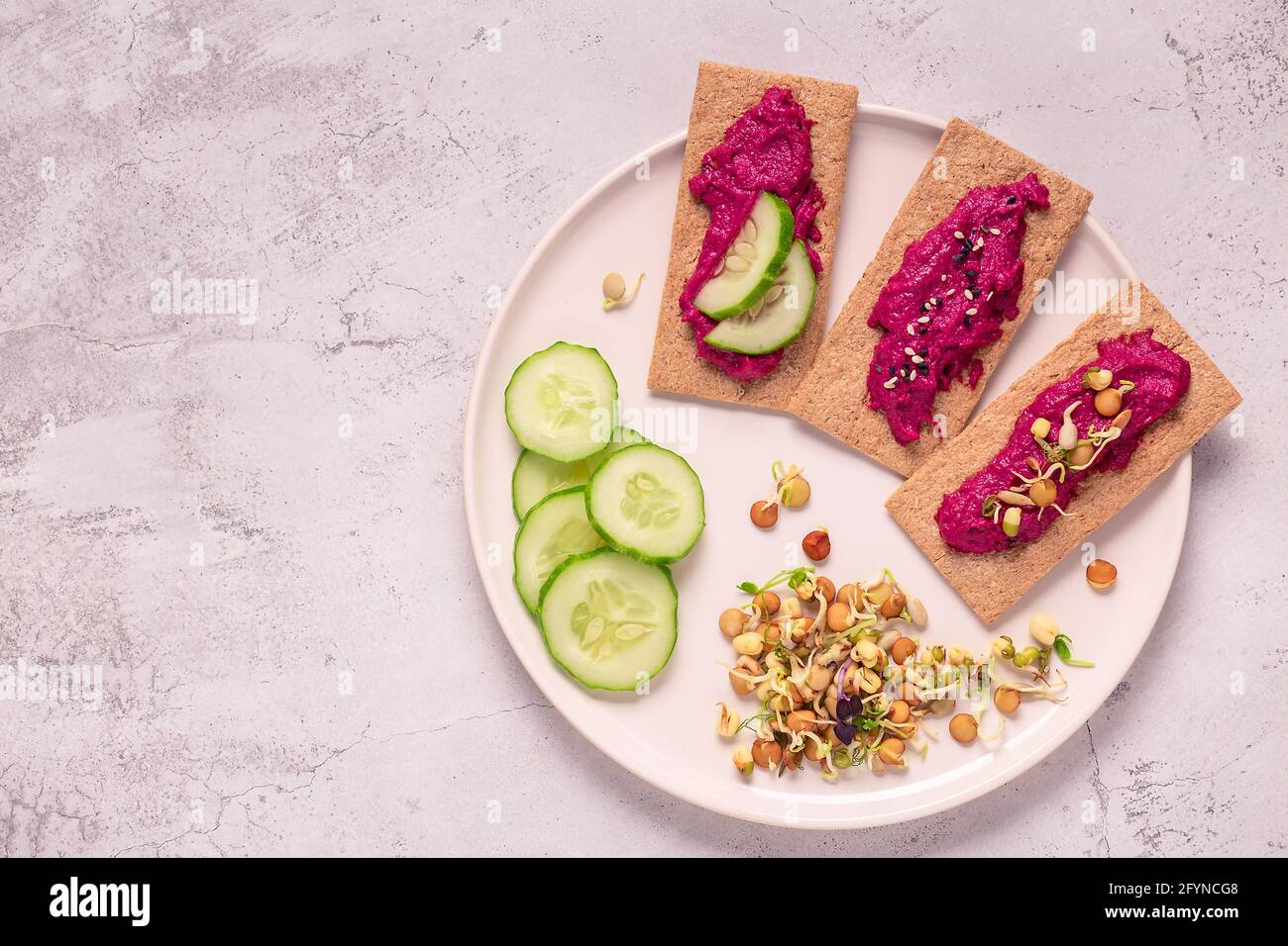 Vegetarischer, veganer Snack - Rote Beete Hummus, gekeimtes Getreide, Gurke und Vollkornknusprige. Stockfoto