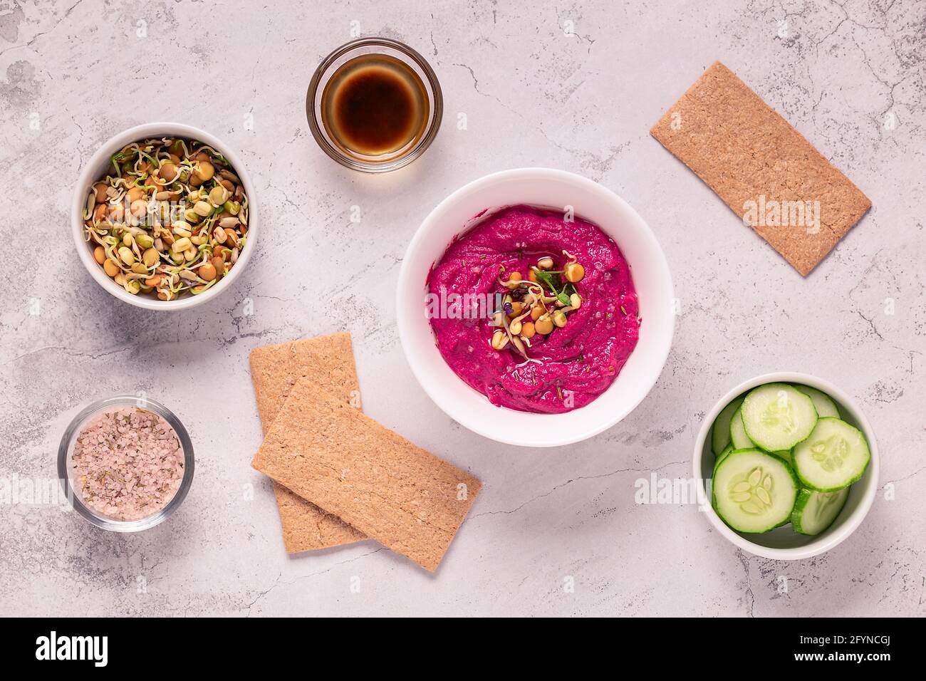 Gerösteter Rübenhummus mit gekeimtem Getreide, Gurke und Knäckebrot, Draufsicht. Stockfoto