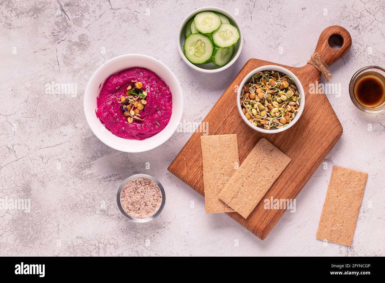 Gerösteter Rübenhummus mit gekeimtem Getreide, Gurke und Knäckebrot, Draufsicht. Stockfoto