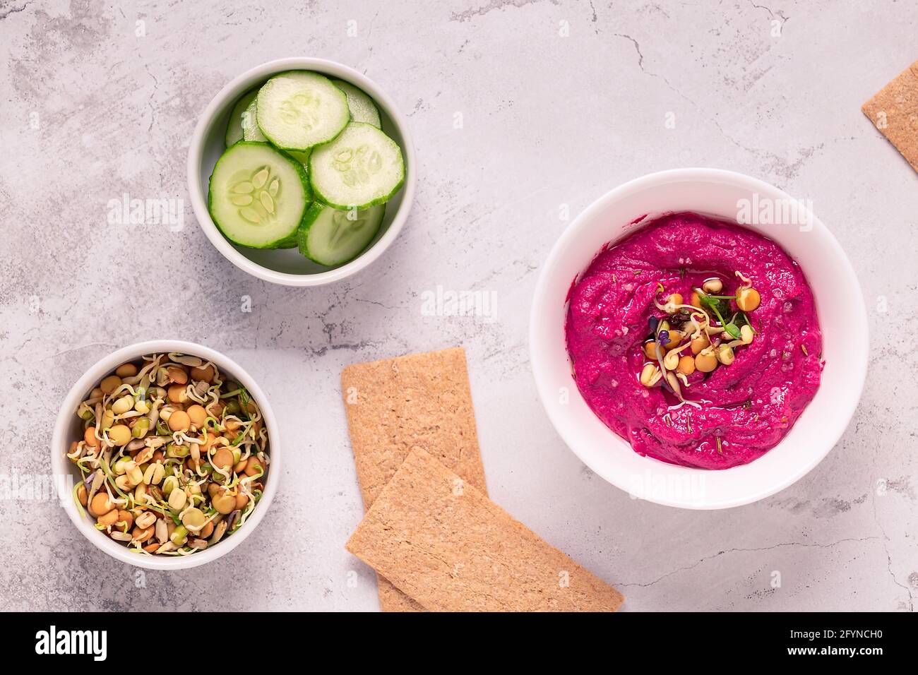 Gerösteter Rübenhummus mit gekeimtem Getreide, Gurke und Knäckebrot, Draufsicht. Stockfoto