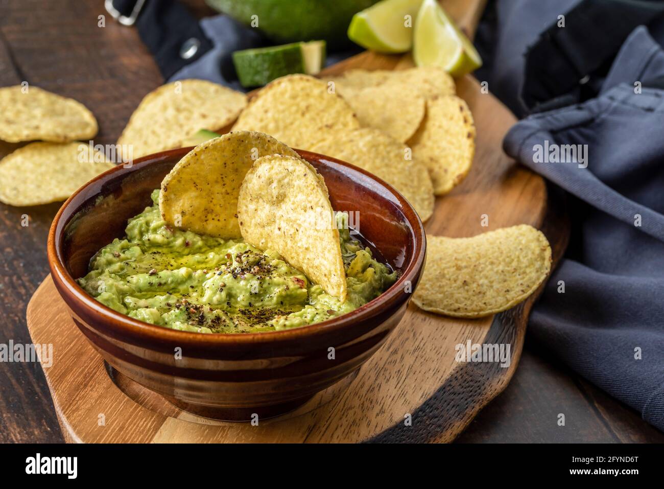 Schüssel mit Guacamole mit Tortilla-Chips auf Holzhintergrund Stockfoto