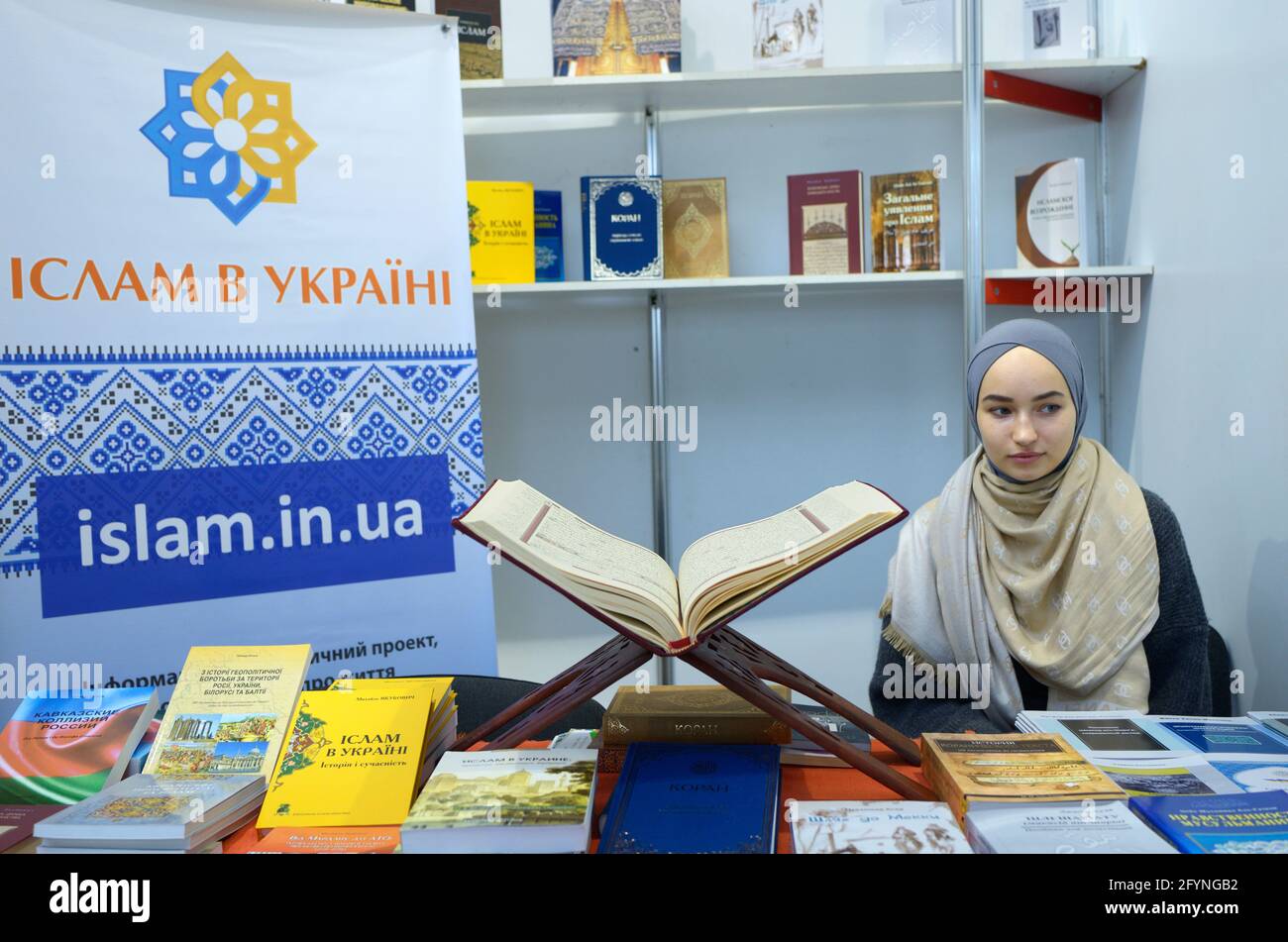Junge hübsche muslimische Mädchen präsentiert islamische Bücher in der Buchhandlung, Koran auf der Theke platziert. Buchmesse Knyzhkovyi Arsenal . 24.Mai 2019. Kiew, Ukrai Stockfoto