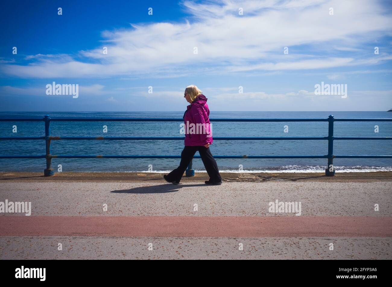 Ältere Frau, die am Meer mit fernem Horizont spazieren geht Stockfoto