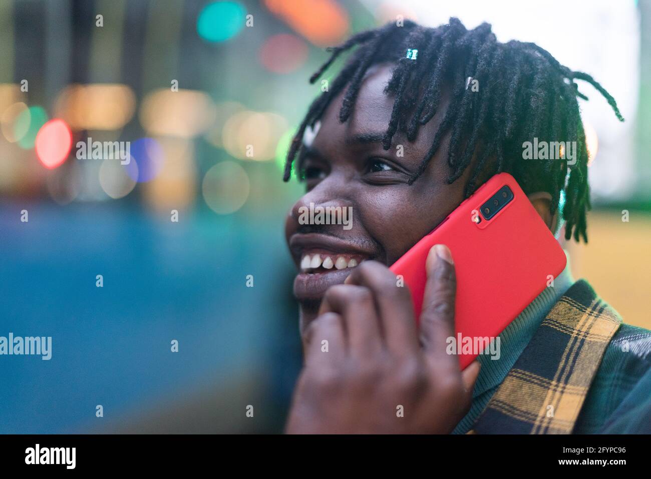 Lächelnder schwarzer Kerl, der in der Stadt auf dem Handy spricht. Stockfoto