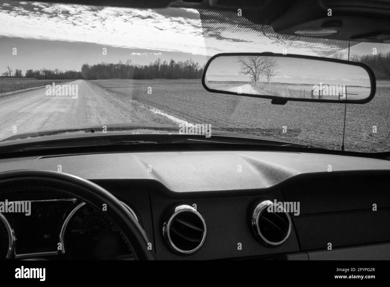Eine unbefestigte Straße im ländlichen Lincoln County, Missouri, USA, wird am 24. Februar 2021 durch die Windschutzscheibe und im Rückspiegel eines Autos gesehen. Stockfoto