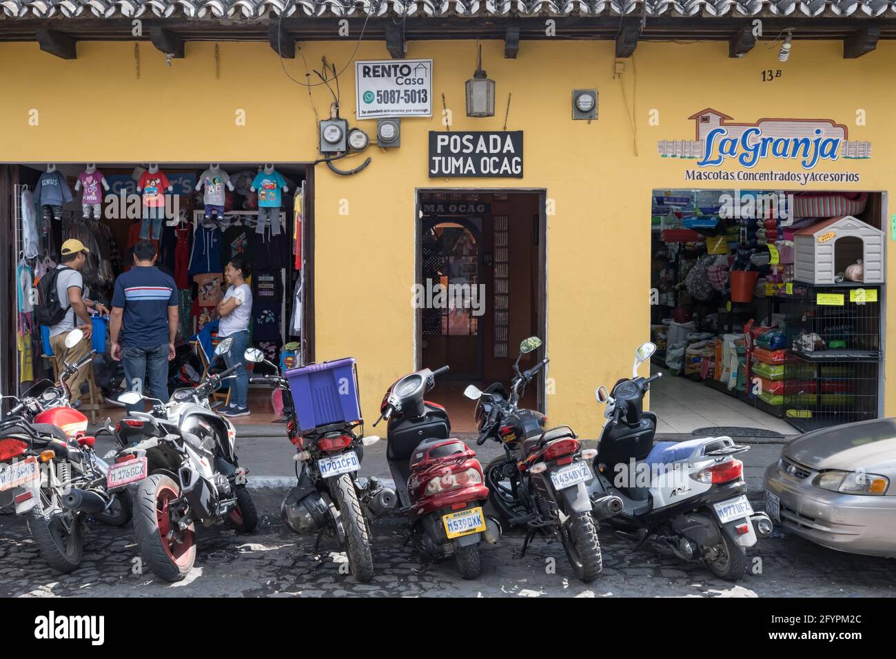 Motorräder parken auf der Straße vor einer Parade von Geschäften in Antigua Guatemala Stockfoto