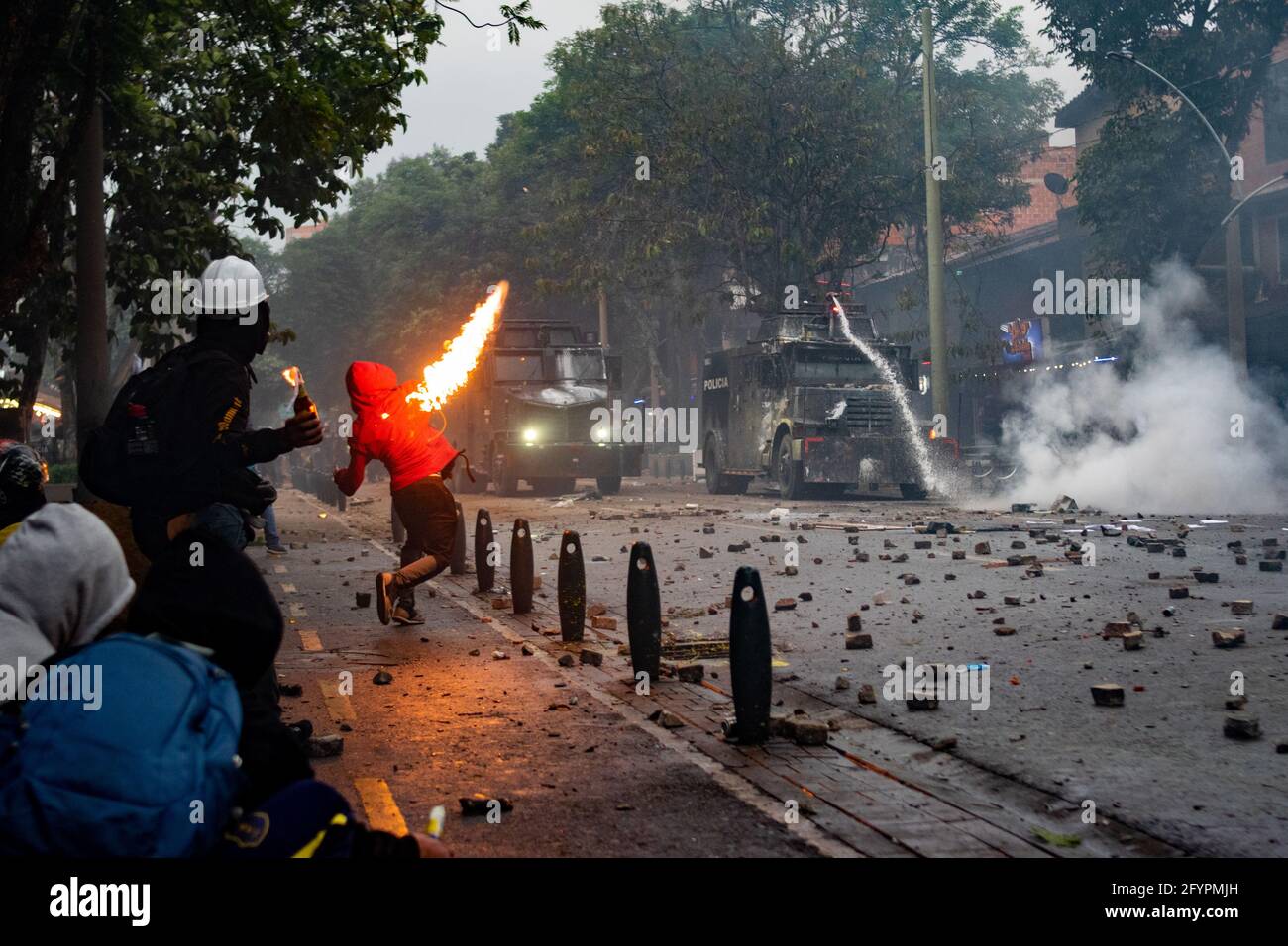 Demonstranten werfen molotow-Bomben auf die gepanzerten Lastwagen der kolumbianischen Bereitschaftspolizei (ESMAD), während Menschen in Medellin gegen den Präsidenten Ivan Duque und gegen die Brutalität der Polizei protestieren, nachdem mindestens 45 Menschen einen Monat lang in Unruhen und Polizeimissbrauch in Behördenfällen getötet wurden. Antioquia - Kolumbien am 28. Mai 2021. Stockfoto