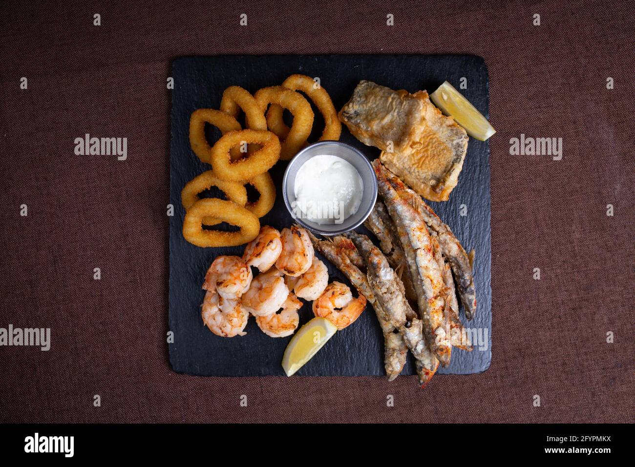 Snacks zu Bier auf einem schwarzen Teller mit Fisch und Zwiebelringe Stockfoto