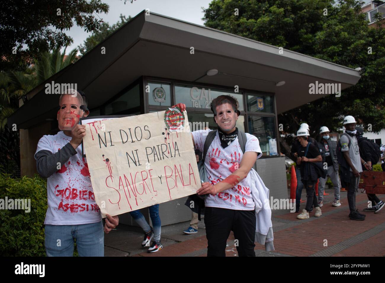 Die Demonstranten tragen Masken von Präsident Iván Duque und Verteidigungsminister Diego Molano und halten ein Schild mit der Aufschrift: „weder gott noch Land, Blut und Kugel.“ an einem neuen Tag der Proteste in Bogotá im Rahmen der einmonatigen Gedenkfeier zum Beginn des nationalen Streiks in Kolumbien gegen die Regierung von Iván Duque am 28. März 2021. Stockfoto