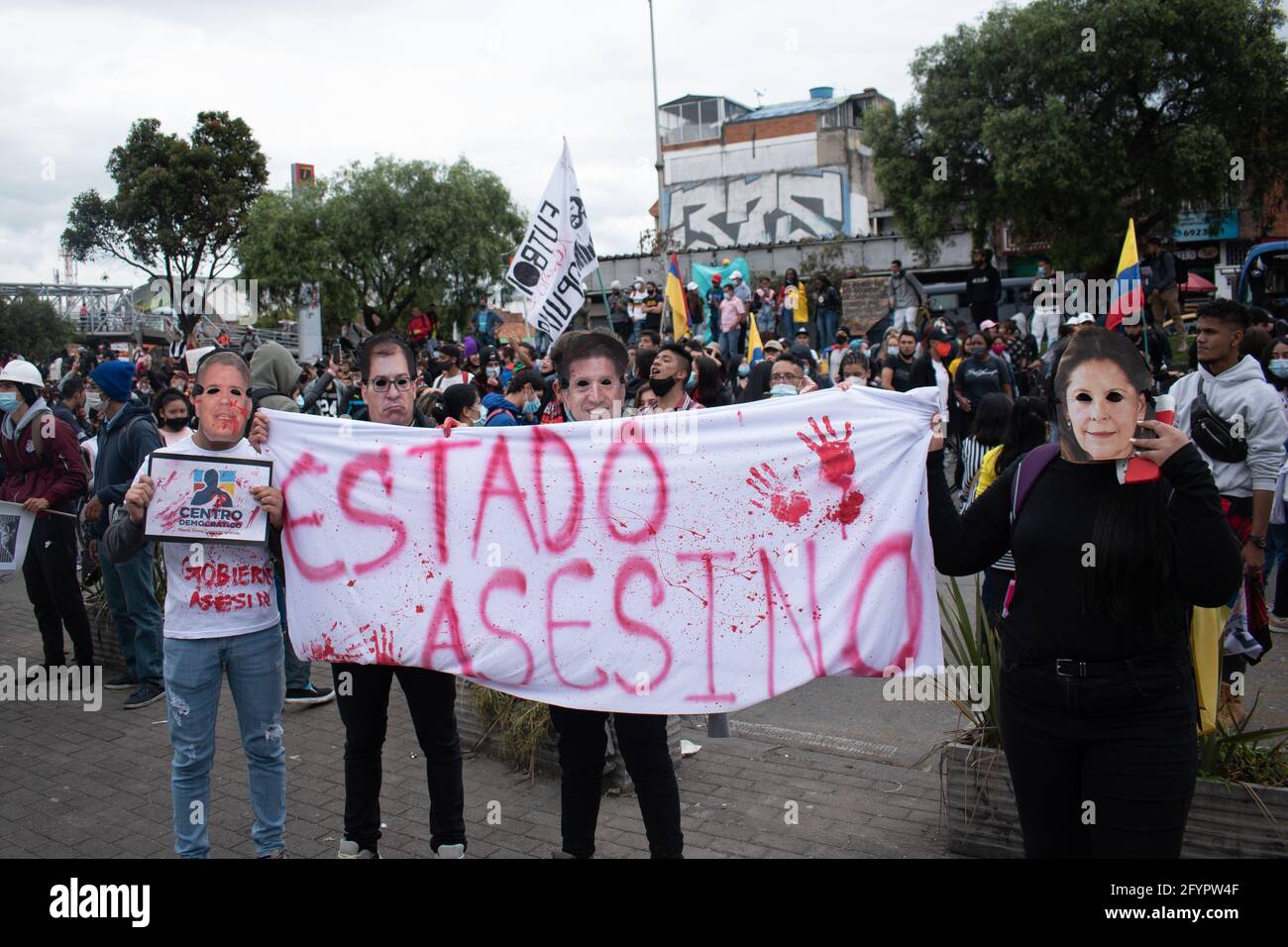 Bogota, Cundinamarca, Kolumbien. Mai 2021. Die Demonstranten tragen Gesichtsmasken von Präsident IvÃ¡n Duque, Vizepräsidentin Martha LucÃ-a RamÃ-rez, Verteidigungsminister Diego Molano und dem ehemaligen Finanzminister Alberto Carrasquilla, während sie ein Schild mit der Aufschrift tragen: „Mörderischer Staat“. An einem neuen Tag der Proteste in BogotÃ¡ im Rahmen der einmonatigen Gedenkfeier zum Beginn des nationalen Streiks in Kolumbien gegen die Regierung von Ivan Duque am 28. März 2021. Quelle: Daniel Romero/LongVisual/ZUMA Wire/Alamy Live News Stockfoto