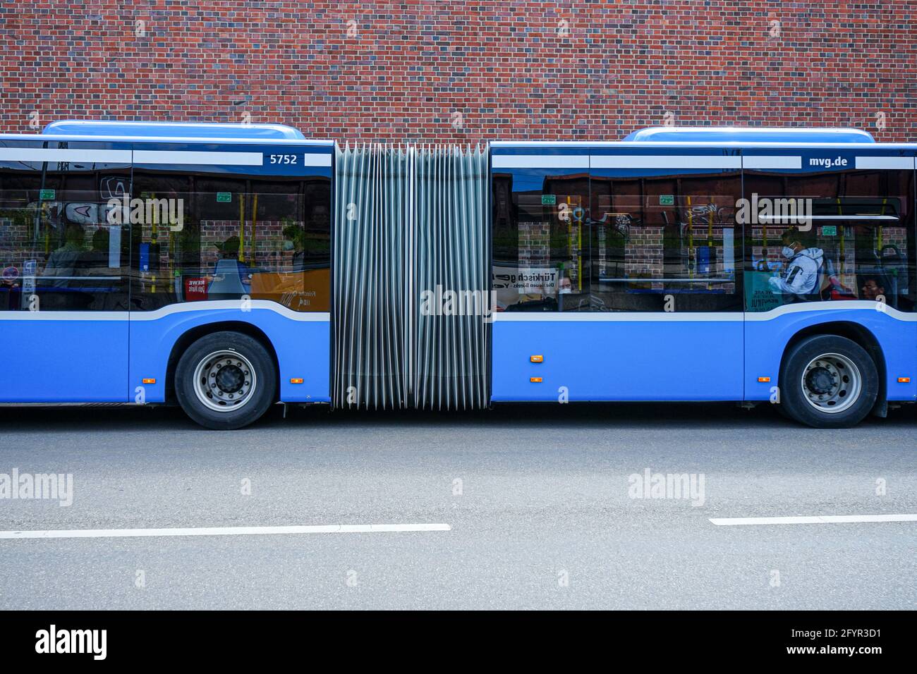 Blick auf einen blauen fahrenden Bus vor einer Backsteinmauer im Schlachthofviertel in München. Stockfoto