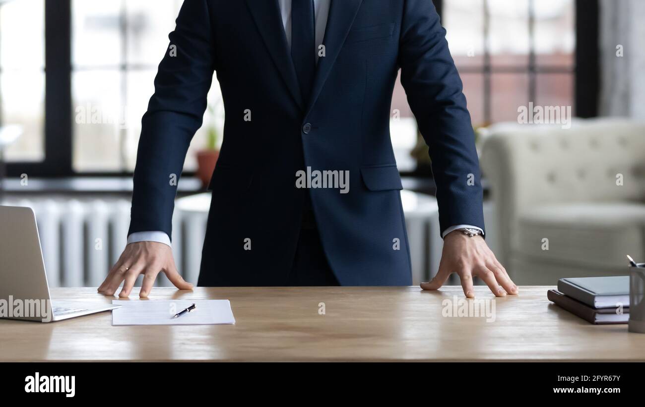 Geschäftsführer, CEO, Inhaber in formeller Klage, der am Schreibtisch steht Stockfoto