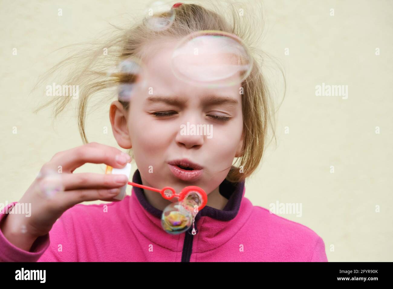 Mädchen lächelt und bläst Seifenblasen. Lustige Aktivitäten im Freien Stockfoto