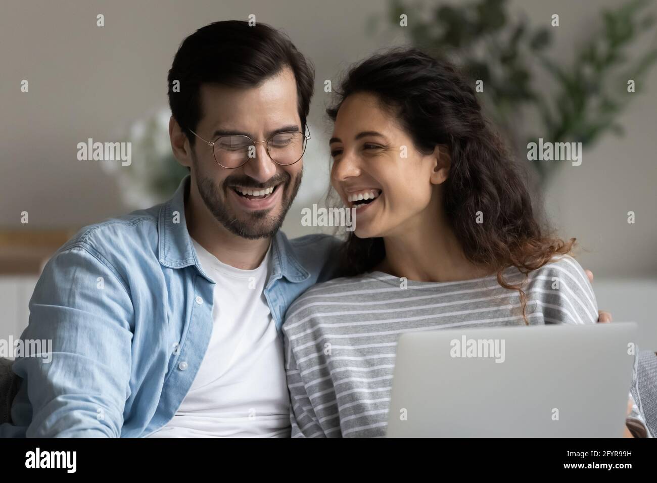 Lächelndes multiethnisches Paar hat Spaß mit dem Computer Stockfoto