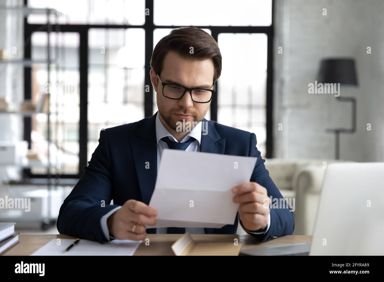Fokussierter Business Leader in formellen Anzug und Brille Lesen Brief Stockfoto