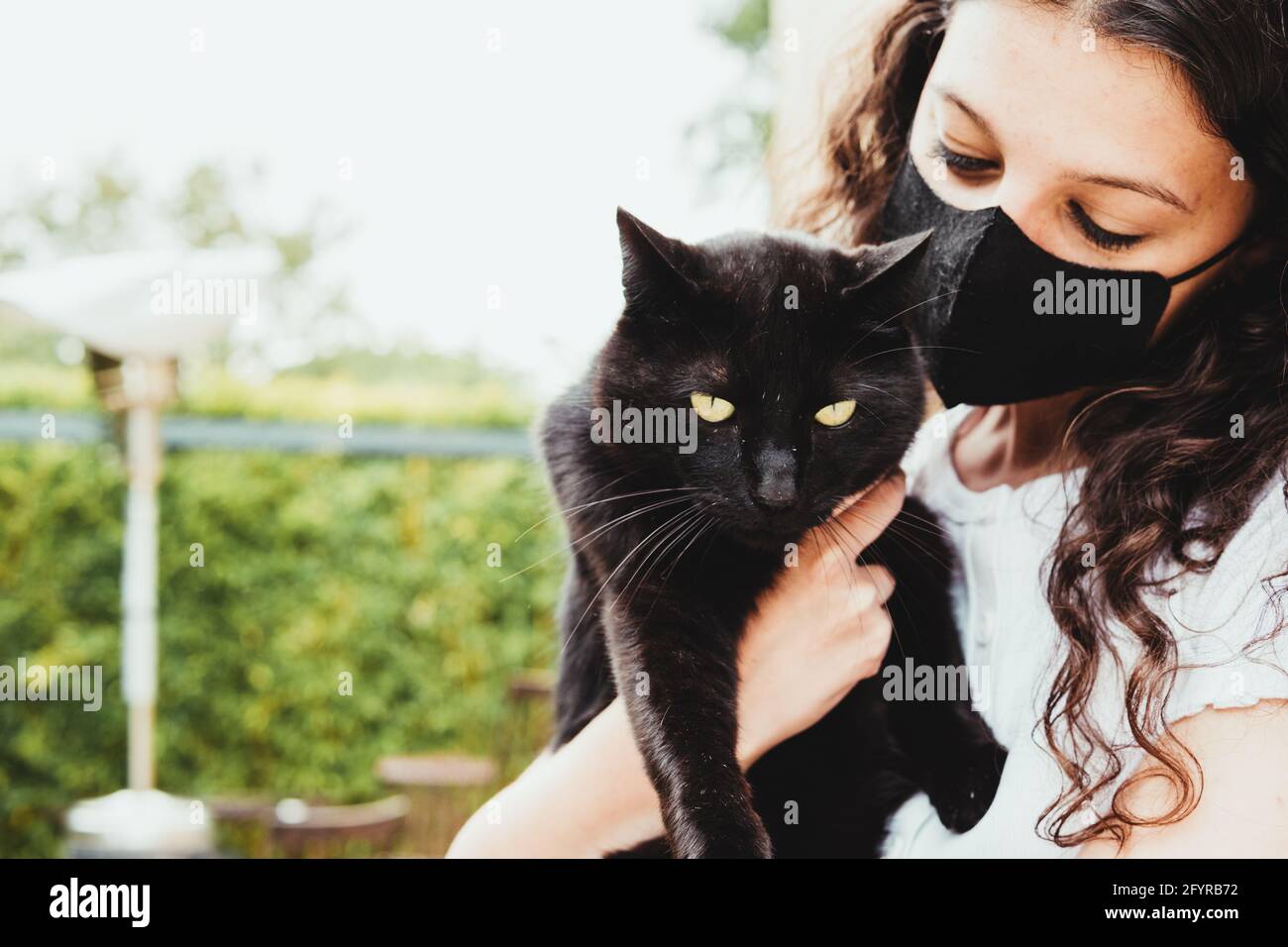 Frau, die schwarze Katze mit grünen Augen hält Stockfoto