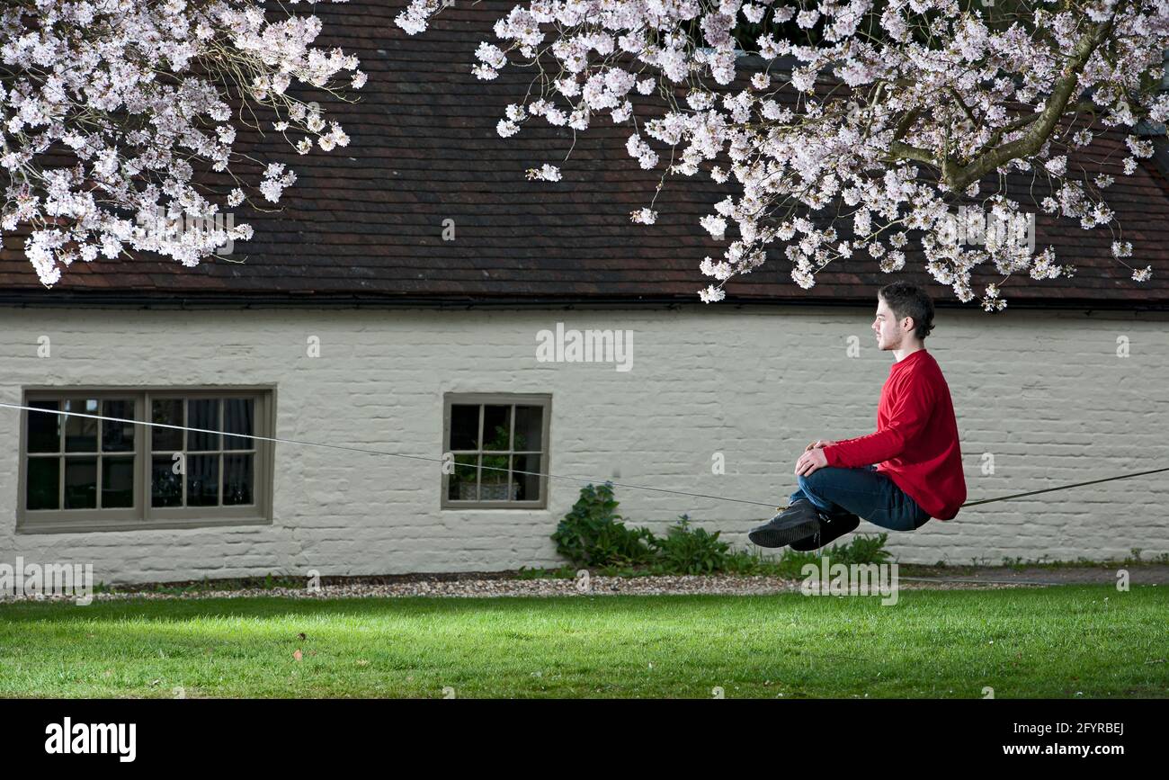 Der junge Mann übt sein Gleichgewicht auf einer schlaffen Linie zwischen zwei Bäumen Stockfoto