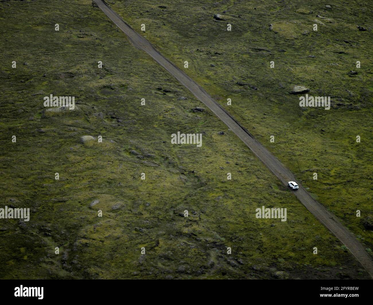 Luftbild eines SUV, das auf einer Schotterstraße durch isländisches Lavafeld fährt Stockfoto