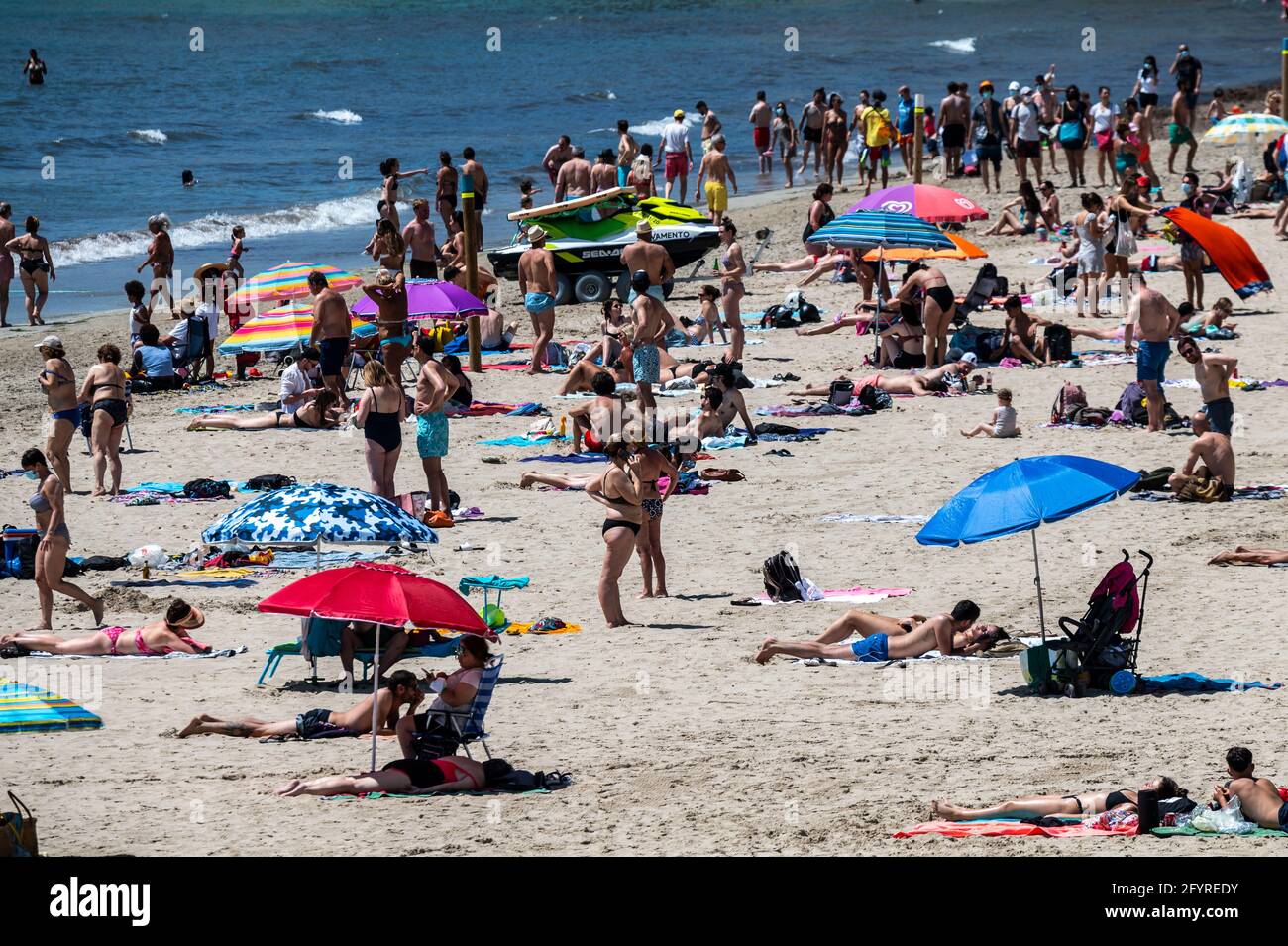 Alicante, Spanien. Mai 2021. Die Menschen genießen hohe Temperaturen in einem überfüllten El Postiguet Strand von Alicante. Die valencianische Gemeinschaft hat am Montag neue Beschränkungsmaßnahmen gegen das Coronavirus (Covid-19) veröffentlicht, unter anderem gegen das Coronavirus, An den Stränden ist es nicht mehr notwendig, in den Ruhezeiten vor oder nach dem Baden eine Maske zu tragen und dabei den Mindestabstand von 1.5 Metern zu anderen Menschen, die nicht zusammen leben, mit einer maximalen Gruppe von 10 Personen einzuhalten. Quelle: Marcos del Mazo/Alamy Live News Stockfoto