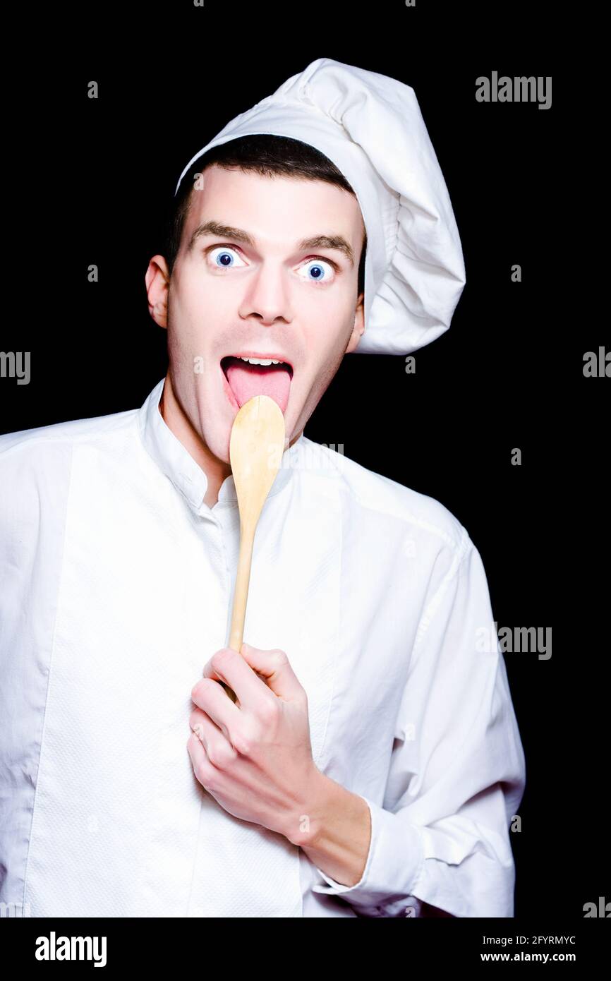 Mann Koch Oder Backer Essen Vom Loffel Mit Einem Uberrascht Und Lustige Ausdruck In Einer Darstellung Von Eine Vorspeise Auf Schwarzem Hintergrund Stockfotografie Alamy