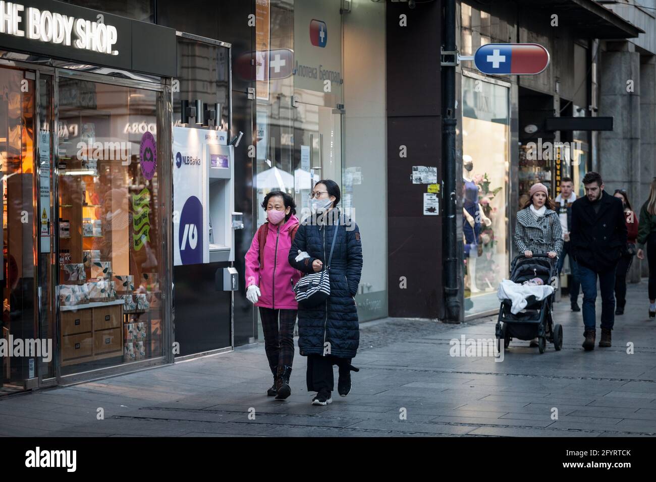 BELGRAD, SERBIEN - 13. MÄRZ 2021: Selektive Weichzeichnung von zwei Frauen, mittleren Alters, asiaten, Freunden, die im Winter mit einer Atemschutzmaske in der spazieren Stockfoto