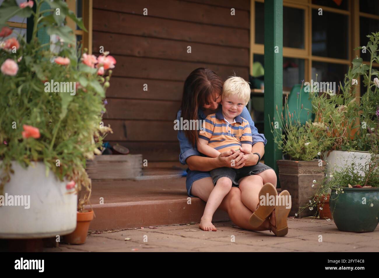 Eine glückliche Mutter mit einem kleinen Jungen, der auf einem sitzt Steinstufen Stockfoto