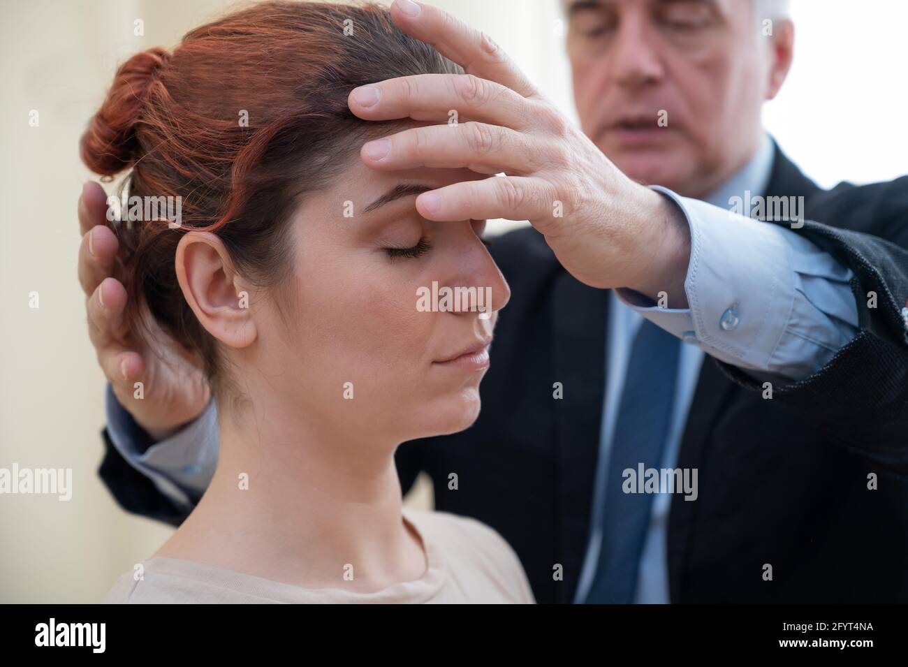 Reifer grauhaariger Mann hypnotisiert kaukasische Frau während der Hypnotherapie-Sitzung. Der Psychologe verwendet alternative Behandlungen für das Unterbewusstsein Stockfoto