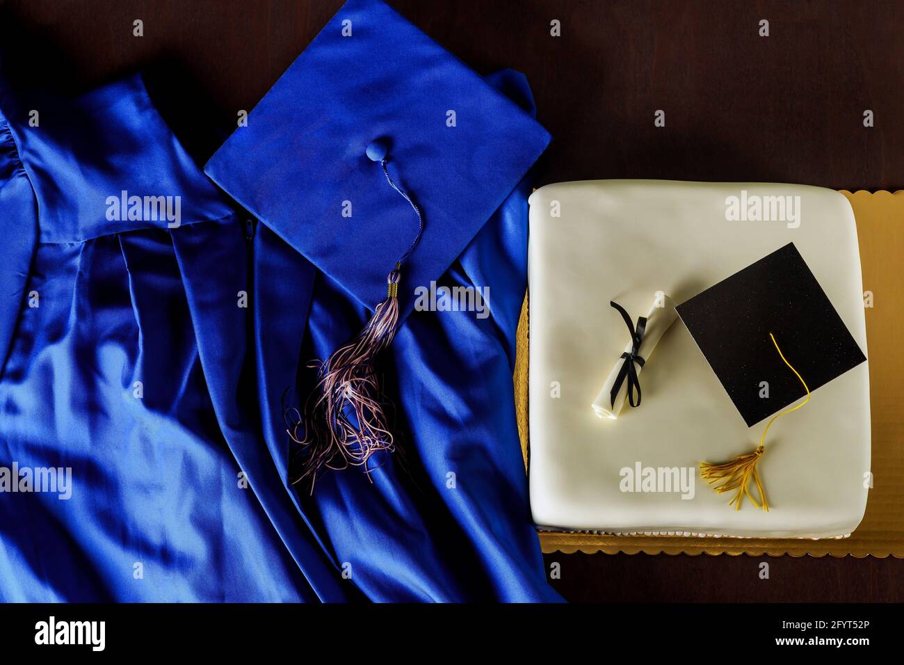 Draufsicht auf Graduierung blauen Hut und Kleid mit Kuchen für die Party. Stockfoto
