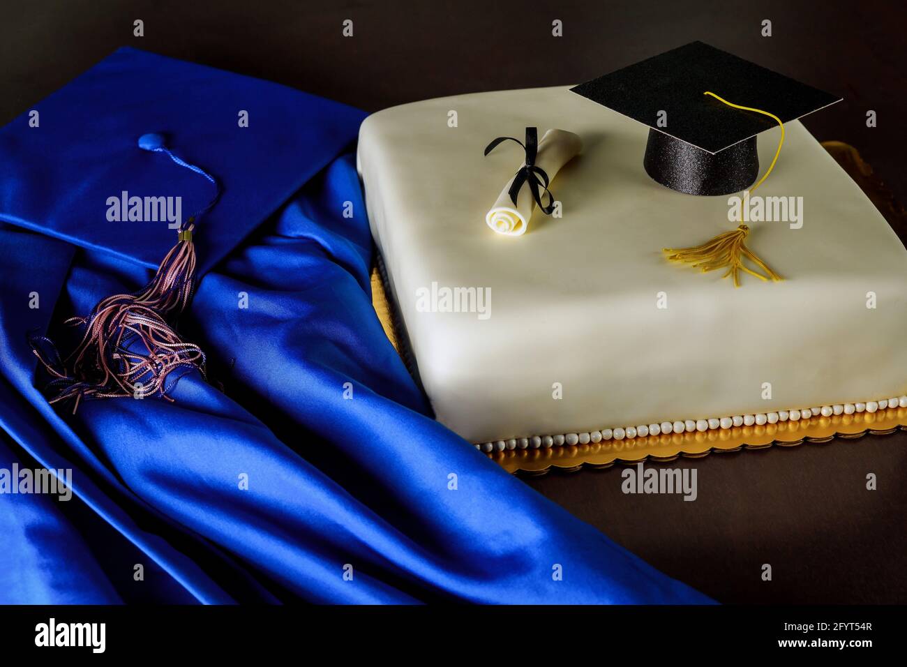 Graduation Fondant Kuchen mit blauem Hut und Kleid auf dunklem Hintergrund. Stockfoto