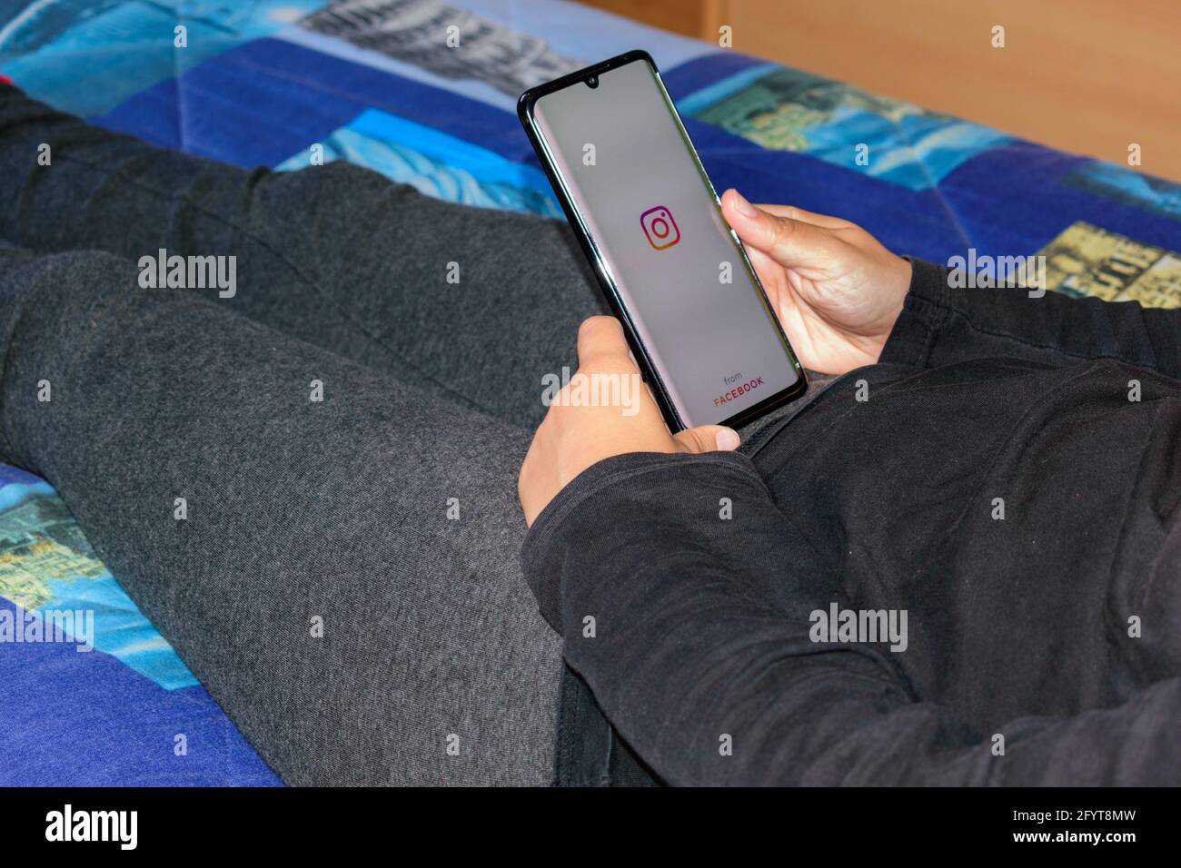 GRANAD, SPANIEN - 16. Mai 2021: Frau liegt im Bett und öffnet die Instagram-App auf dem Handy Stockfoto