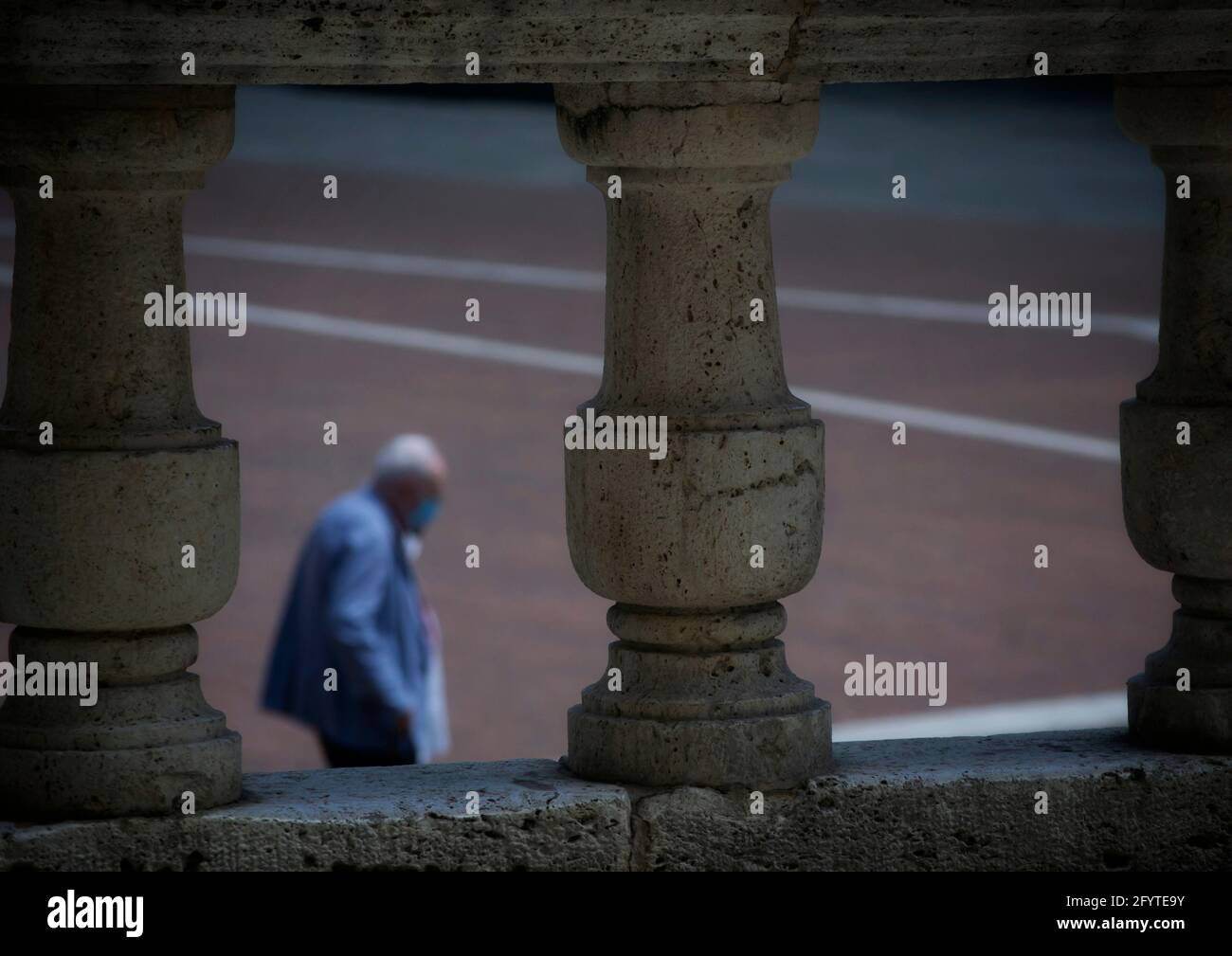 Arezzo, Italien, 28. Mai 2021, antike Steinsäulen mit einem älteren weißhaarigen Herrn, der im unscharfen Hintergrund spaziert Stockfoto