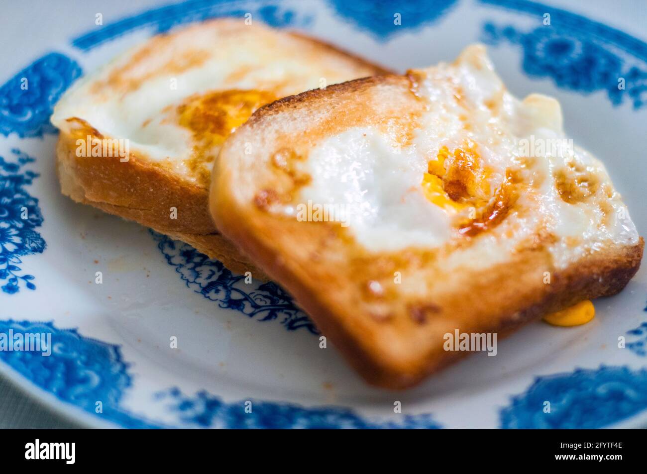 Eierbrot auf dem Teller, fotografiert mit natürlichem Licht. Golden French Toast mit Butter und Ei. Frühstück mit Brot. Englisches Frühstück. Gesundes Frühstück Stockfoto