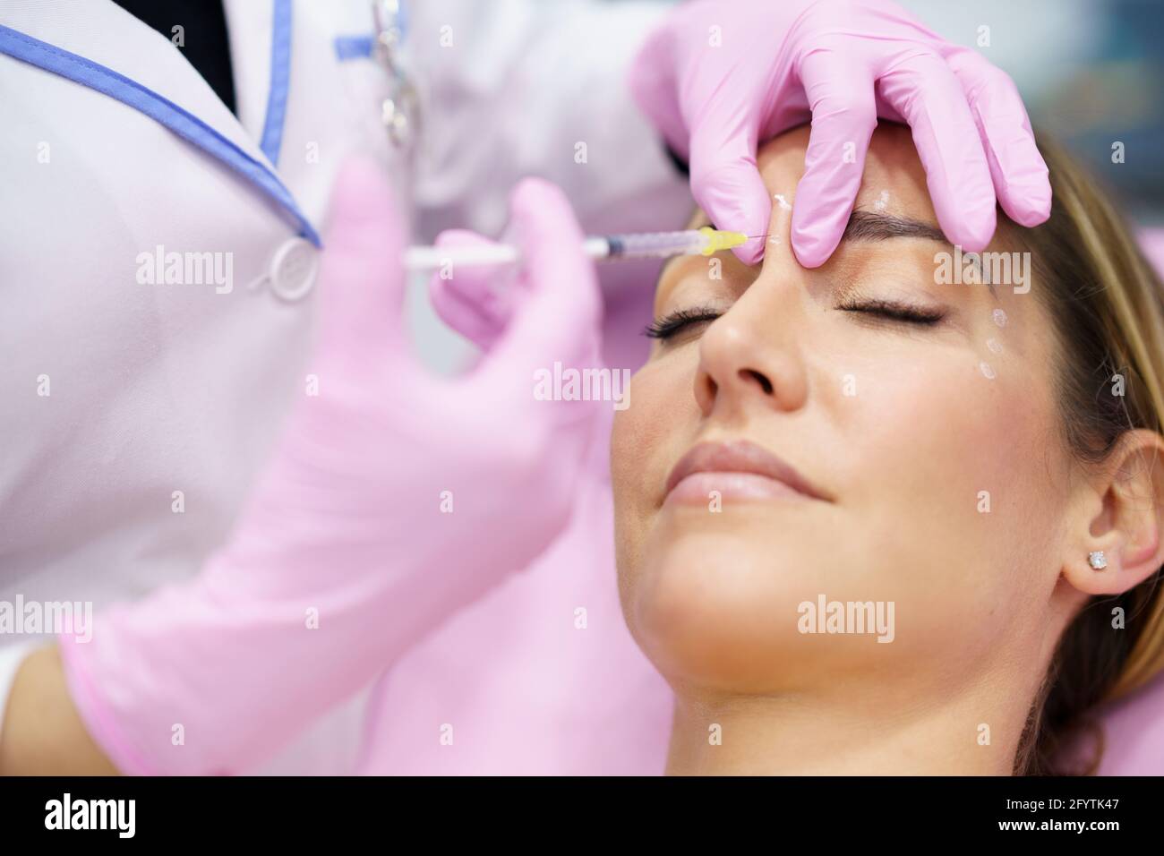 Die ästhetische Ärztin injiziert Botulinumtoxin in die Stirn ihrer Patientin mittleren Alters. Stockfoto