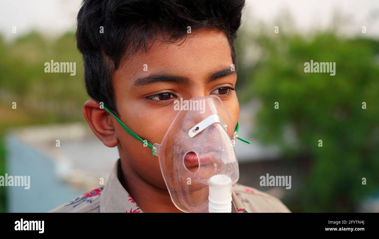 Ein kleiner Junge, der sich mit der Covid-19-Krankheit infiziert hat. Kinderpatient inhaliert Sauerstoff mit Maske zu Hause. Indischer Junge, der Asthma, Lungen und Cou behandelt Stockfoto