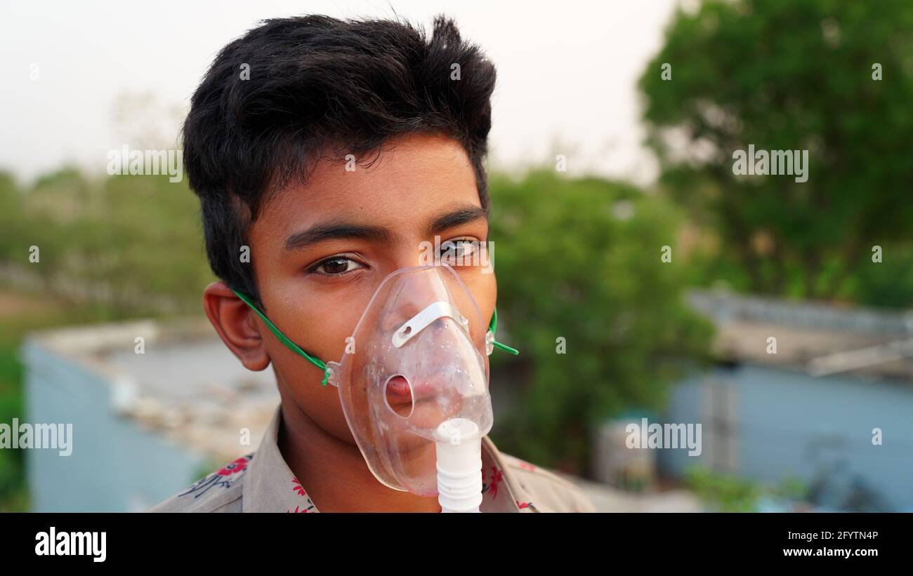Ein kleiner Junge, der zu Hause mit Sauerstoffmaske atmet. Indischer Kinderpatient mit Covid 19-Krankheit infiziert. Indischer Junge, der die Behandlung von Asthma, Lungen nimmt. Stockfoto