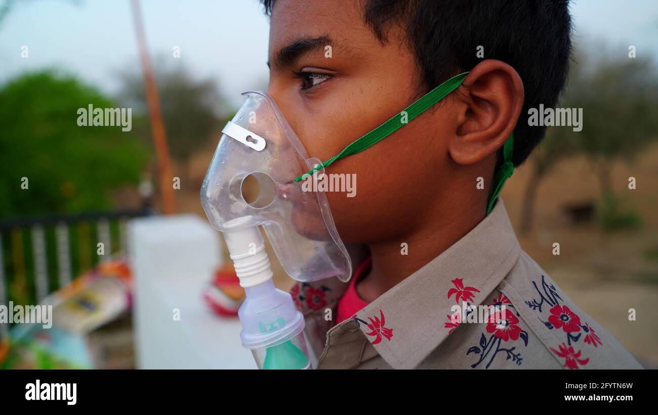 Ein kleiner Junge, der zu Hause mit Sauerstoffmaske atmet. Indischer Kinderpatient mit Covid 19-Krankheit infiziert. Indischer Junge, der die Behandlung von Asthma, Lungen nimmt. Stockfoto