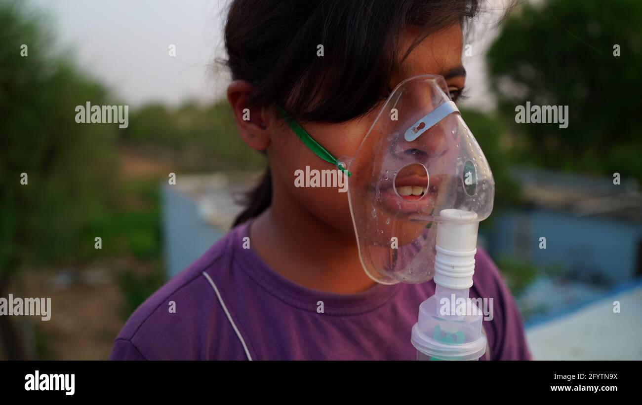Ein kleines Baby atmet mit Sauerstoffmaske zu Hause. Indian Girl Patient infiziert mit Covid 19 Krankheit.Frau, die Behandlung von Asthma, Lungen. Stockfoto