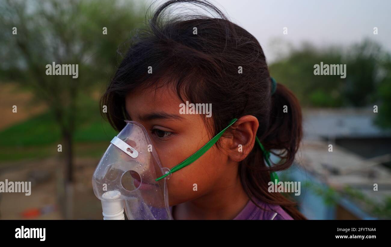 Ein kleines Baby atmet mit Sauerstoffmaske zu Hause. Indian Girl Patient infiziert mit Covid 19 Krankheit.Frau, die Behandlung von Asthma, Lungen. Stockfoto