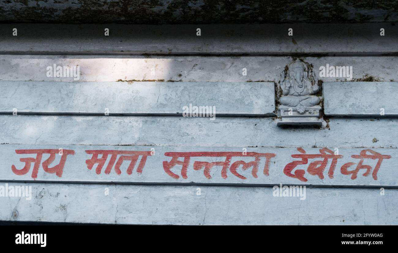 Eine Aufnahme eines religiösen Textes, der auf einer Mauer in hindi vor einem Tempel in Nordindien geschrieben wurde. Stockfoto