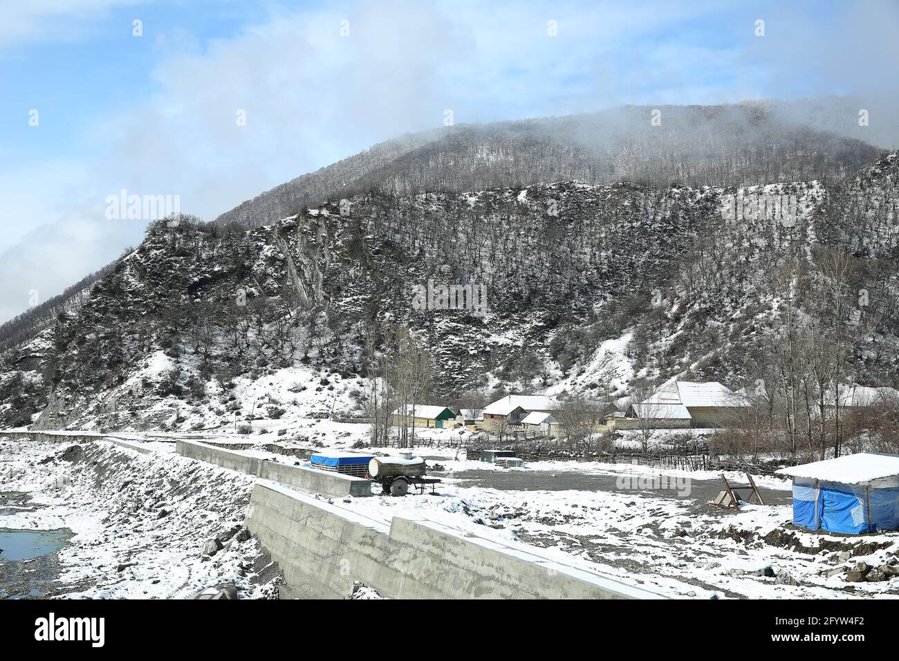 Betonkörper im Fluss . Betonmauern zum Schutz des Dorfes vor starken Überschwemmungen. Winter und Berge . Am Fuße des Berges ist Nebel Stockfoto