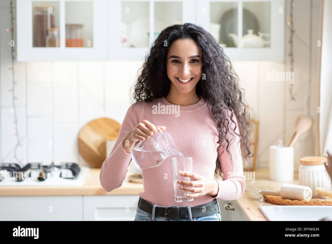 Gesunde Flüssigkeit. Porträt Einer Jungen Frau, Die Zu Hause In Der Küche Wasser Trinkt Stockfoto