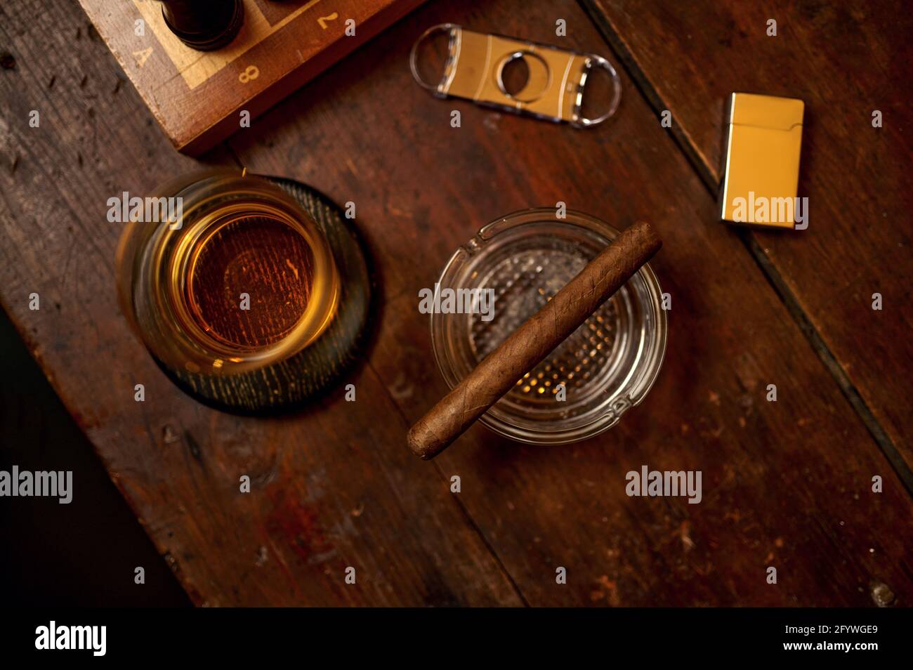 Zigarre in Aschenbecher, Alkohol, Feuerzeug und Guillotine Stockfoto