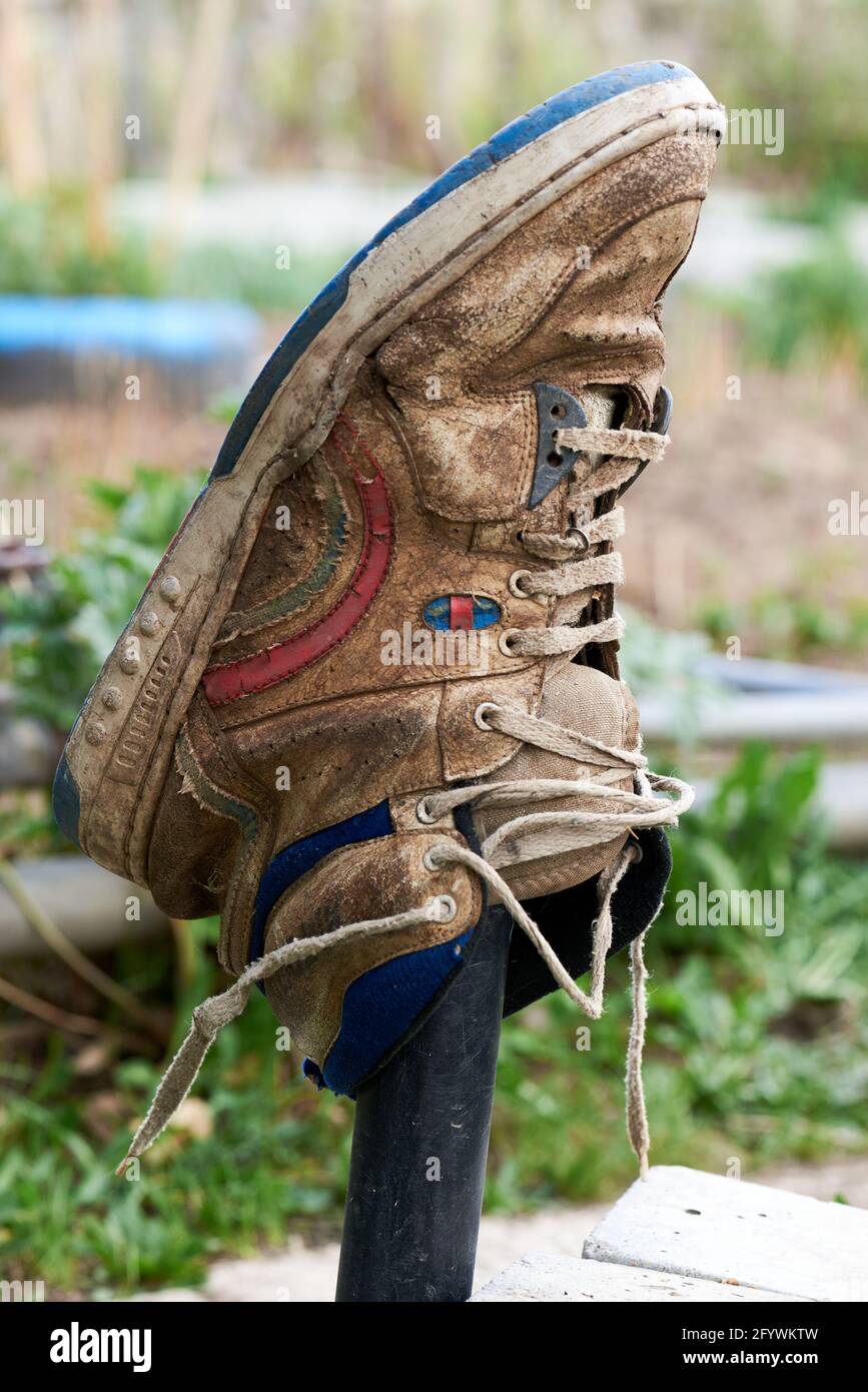 Nahaufnahme eines braunen Sneakers, der an einem Zaun hängt Ein Dorf Stockfoto