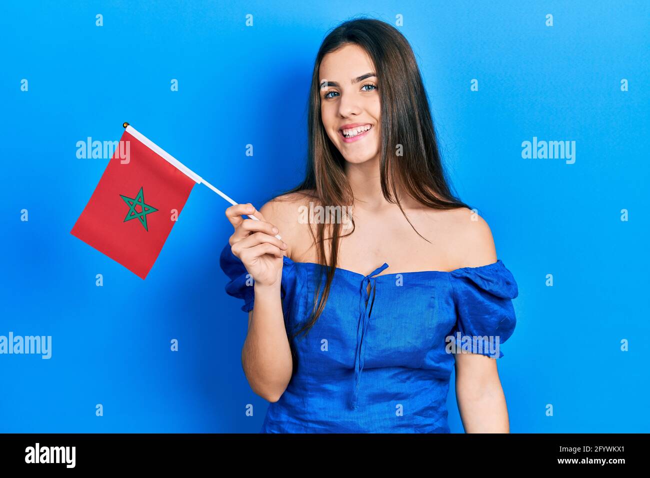 Junge Brünette Teenager hält marokko Flagge positiv und glücklich Stehen und lächeln mit einem selbstbewussten Lächeln, das Zähne zeigt Stockfoto